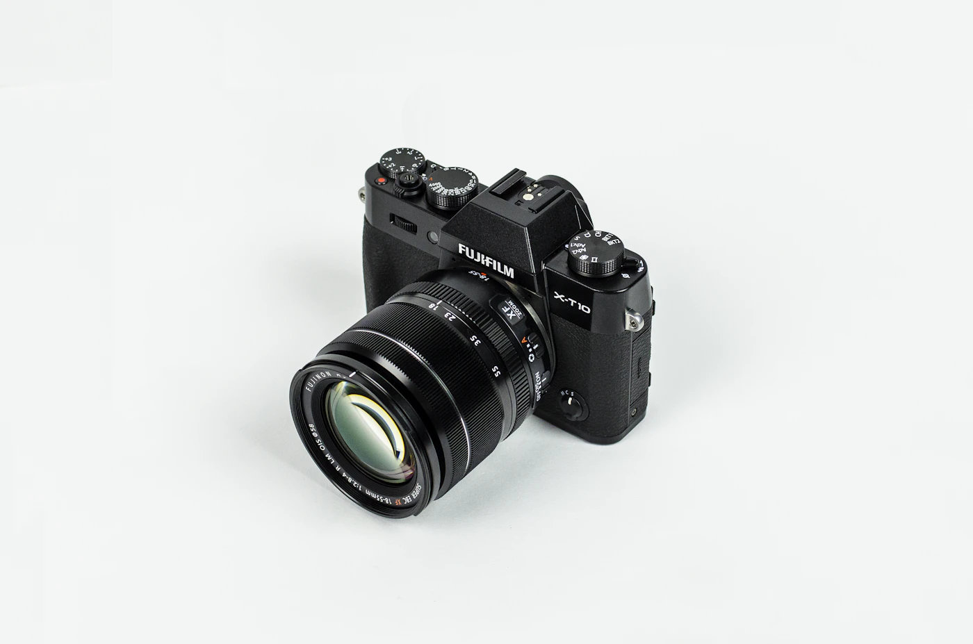 A black mirrorless camera and lens on a pale studio surface