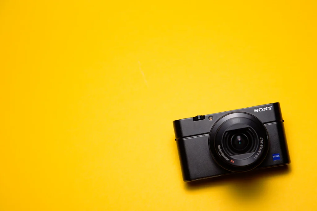 A black compact camera on a yellow background