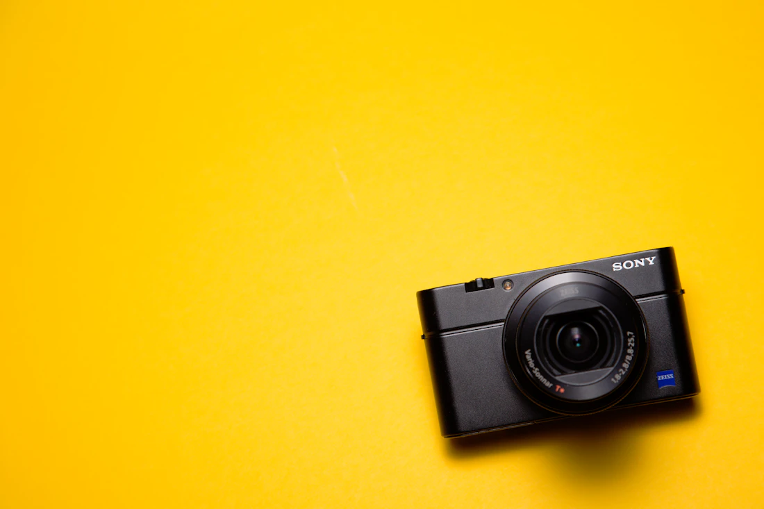 A black compact camera on a yellow background
